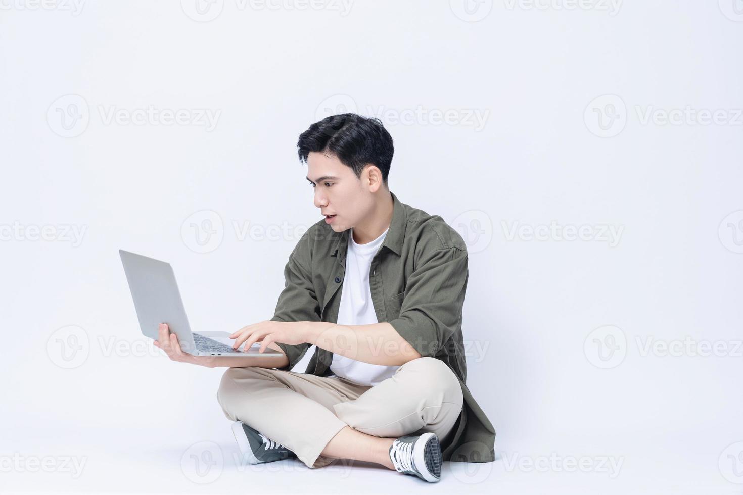 Young Asian business man sitting and using laptop on background photo