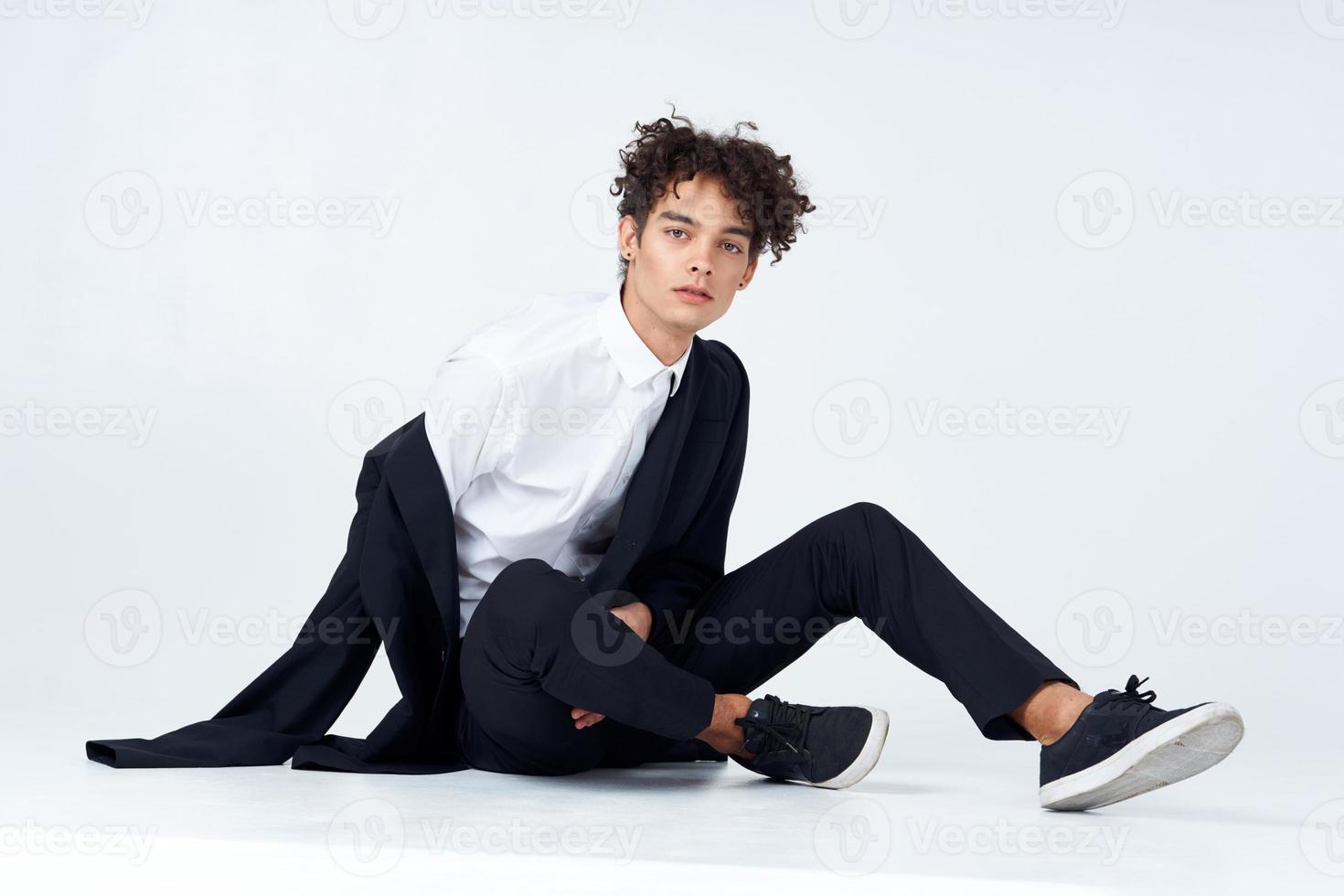 handsome man in suit sitting on the floor fashion confidence light background photo