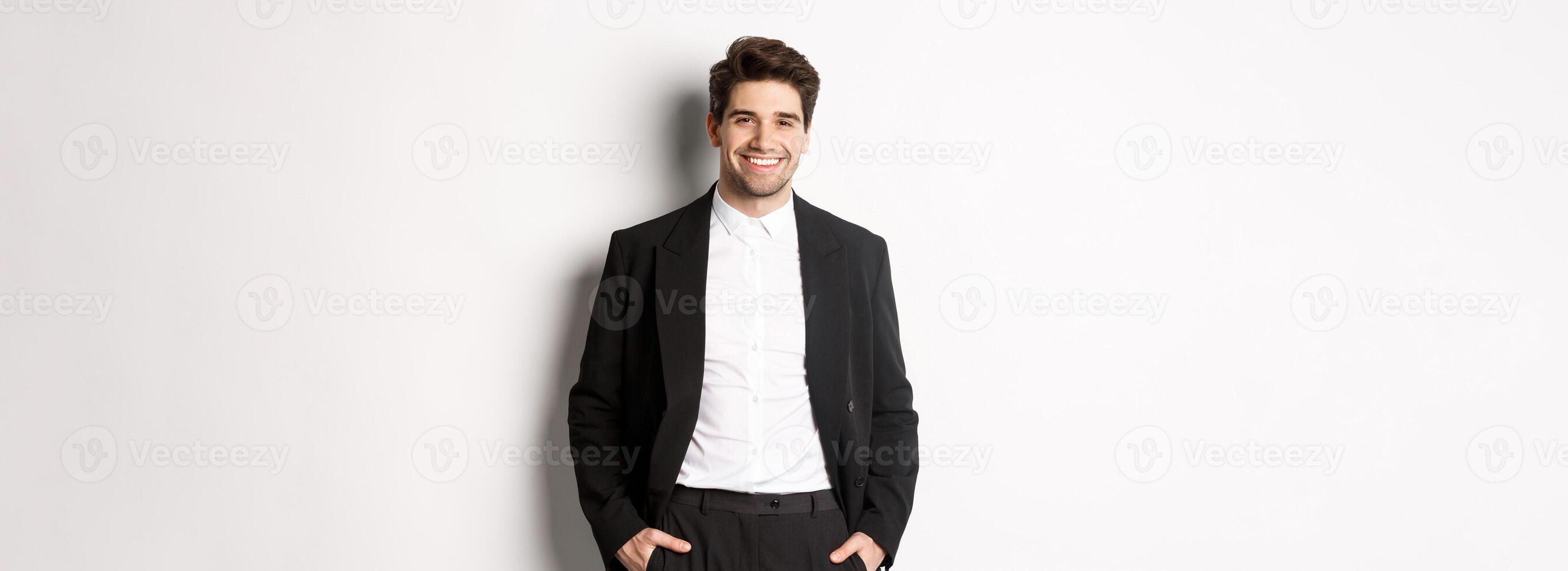 imagen de hermoso caucásico hombre en fiesta traje, sonriente complacido, atender formal evento, en pie terminado blanco antecedentes foto