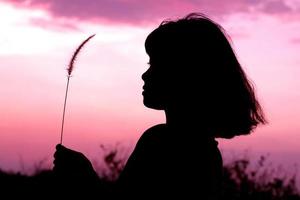 silueta mediana de una mujer o una mujer de pie con el fondo de la puesta de sol en el cielo a la hora de la puesta del sol. foto