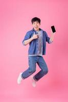 Young Asian man jumping on blue background photo