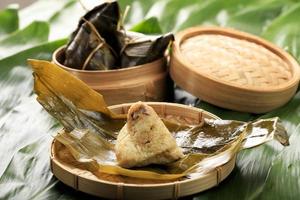 Zongzi or Bakcang, Chinese Savoury Sticky Rice Dumplings in Bamboo Leaves Wrapping. Fresh Concept with Fresh Bakcang  Leaves. photo