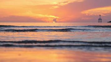 bela vista do pôr do sol incrível na praia. pôr do sol colorido da praia do oceano com céu dourado e ondas suaves. férias de verão e conceito de viagens. video