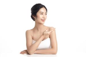 Asian woman with a beautiful face and Perfect clean fresh skin. Cute female model showing concept or idea on copy space on white isolated background. Facial treatment, Cosmetology, beauty Concept. photo