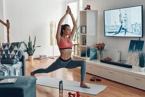 Attractive fit young woman in sports clothing working out while spending time at home photo
