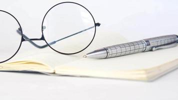 Notebook open with ballpoint pen and round framed glasses video