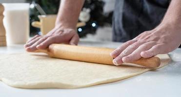 Male chef working with dough, cooking cinnamon rolls photo