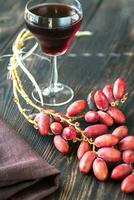 Glass of red wine with bunch of dates photo