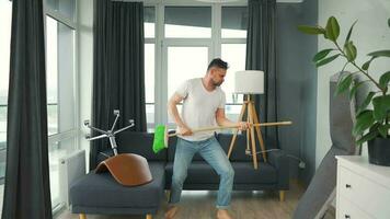 homme nettoyage le maison et ayant amusement dansant avec une balai. lent mouvement video