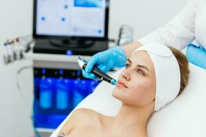 cara piel cuidado. de cerca de mujer consiguiendo facial hidro microdermabrasión peladura tratamiento a cosmético belleza spa clínica. hidra vacío limpiador. exfoliación, rejuvenecimiento y hidratación cosmetología. foto