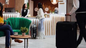 hotell personal tillhandahålla lyx concierge tjänster för klient anländer på främre skrivbord, portion med vagn påsar och registrerar bearbeta. asiatisk kvinna bekräftande uppkopplad rum bokning för kolla upp i. video