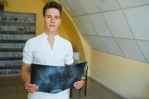 Attractive doctor examining an x-ray and smiling at the camera photo