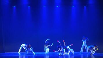 Silhouetted dancers on stage with blue lighting, performing a contemporary dance routine. video