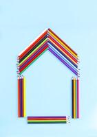 Color pencils in a shape of house on light blue background. photo