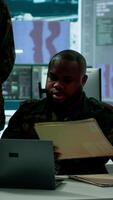 verticale nel un' alto Tech militare ufficio, soldati squadra analizzare vero tempo dati raccolto di sorveglianza sistema. personale interpretare intelligenza e coordinata operazioni per garantire nazionale difesa. telecamera un. video