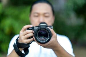 Asian man holds the Medium Format Camera in his hand and focus to shoot in front of him. photo