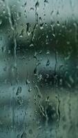queda gotas em vidro. molhado janela em borrão fundo. chuva gotas corrida baixa a janela superfície. vertical video