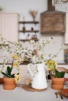 A bouquet of spring white flowers on branches in a vase on the kitchen table. Scandinavian style of the interior and decor of the house photo