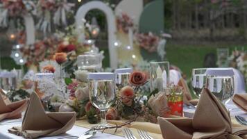 Beautiful decorated white tables for a wedding in glamour style with floral bouquets and candles. video
