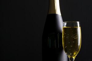 champagne wine glass and bottle on black background photo