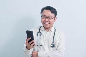 Joyful Asian man doctor, nurse using phone isolated white background. photo