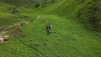 Aerial view of a group of hikers with backpacks climbing up the mountainside video