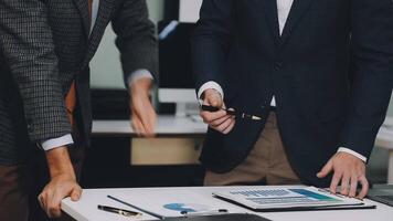 Two business men are standing over a desk with a laptop video