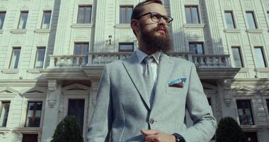 uma à moda, bem vestido homem dentro uma terno posando ao ar livre dentro frente do uma vibrante urbano fundo video