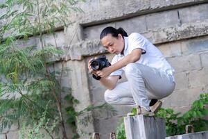 Professional Asian Chinese - Thai Camera man posture 9and focus in viewfinder and LED screen on mirrorless camera medium format in construction concrete area. photo